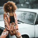 Woman Wearing Brown Floral Print Coat and Pants Sitting on Car