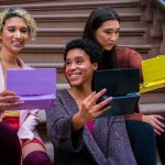 woman in purple sweater holding ipad beside woman in black sweater