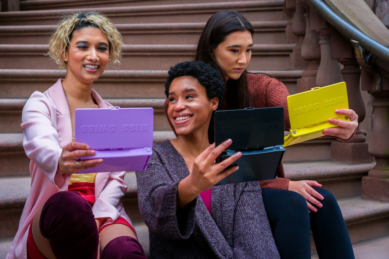 woman in purple sweater holding ipad beside woman in black sweater